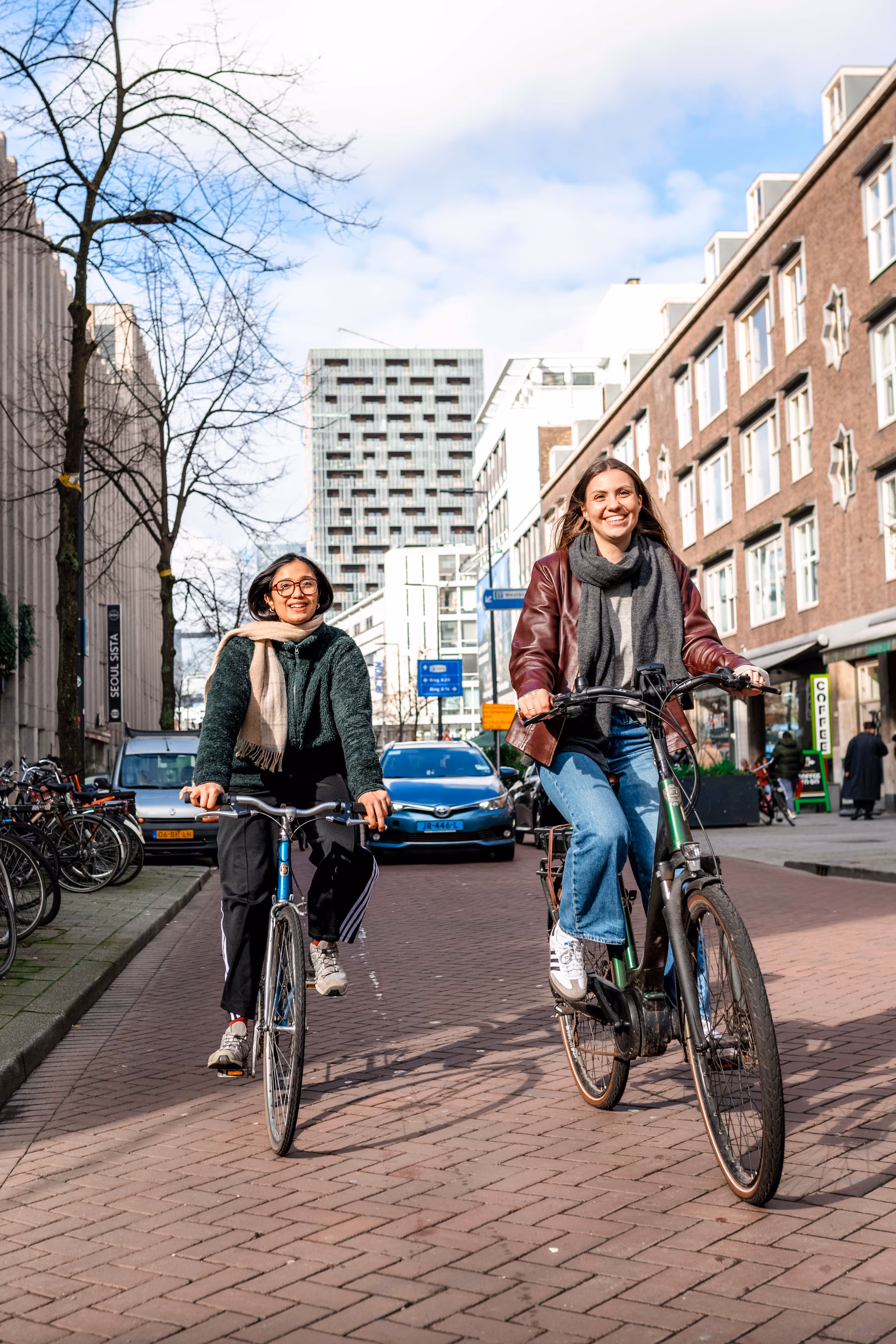 Twee meiden lachend naast elkaar op de fiets